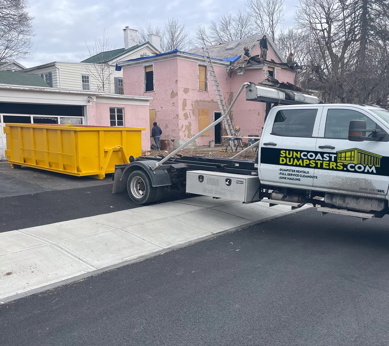 Suncoast Dumpster Rentals truck delivering a roll-off dumpster to a renovation project